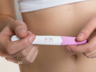 Lady holding a positive pregnancy test with two lines